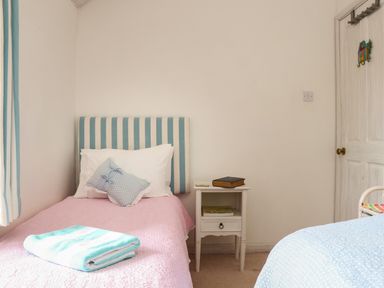 A bedroom with two single beds a bedside table and a door at Rose Cottage in Lower Bostraze near St Just