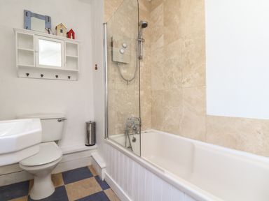 A bathroom with a bathtub shower combination toilet and wall-mounted cabinet at Rose Cottage in Lower Bostraze near St Just