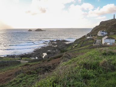 A rocky coastline with houses on a hillside and the ocean in the background at Rose Cottage in Lower Bostraze near St Just