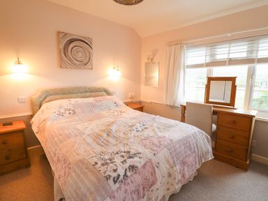 A bedroom with a bed a desk with a mirror and two bedside tables at Morlyn Guest House Apartment in Llandanwg near Harlech