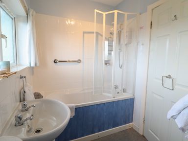 A bathroom with a sink and a bathtub with a shower screen at Morlyn Guest House Apartment in Llandanwg near Harlech