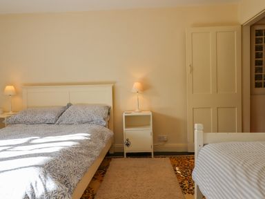 A bedroom with two beds a nightstand with a lamp and a door at Bodkin Cottage in Dunster