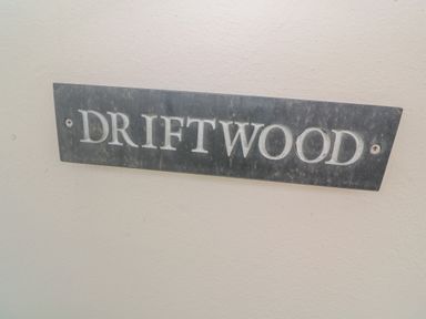 A metal plaque with the word Driftwood on a beige wall at Driftwood in Marazion