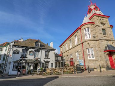 Two buildings with outdoor seating area and benches on the street at Driftwood in Marazion