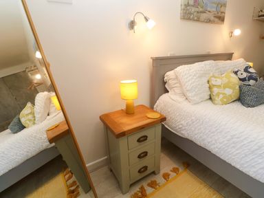 A bedroom with a bed and nightstand at Driftwood in Marazion