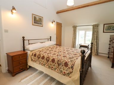 A bedroom with a bed a wooden chest of drawers a nightstand and a window with curtains at The Nook in Jack's Green near Painswick