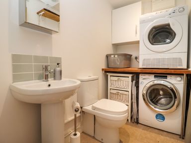 A laundry room with a washing machine dryer toilet and sink at The Nook in Jacks Green near Painswick