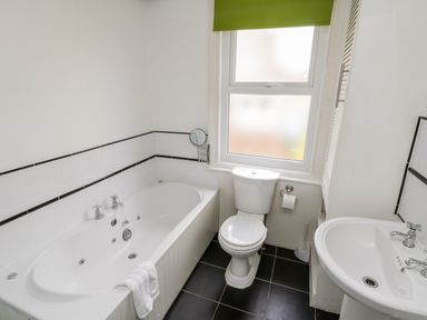 A bathroom with a bathtub a toilet a sink and a window with a green blind at 89 Caledonia Street in Scarborough