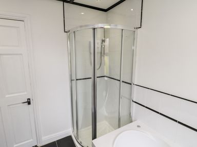 A bathroom with a corner glass shower enclosure and a white sink at 89 Caledonia Street Scarborough