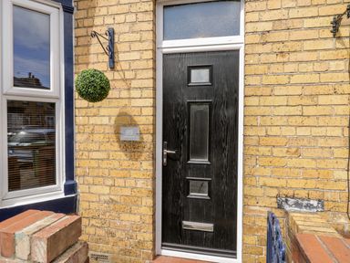 A black front door with a mail slot and frosted window panels on a yellow brick wall at 89 Caledonia Street Scarborough