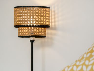 A lamp with a woven shade on a black stand casting light against a white wall at 89 Caledonia Street in Scarborough