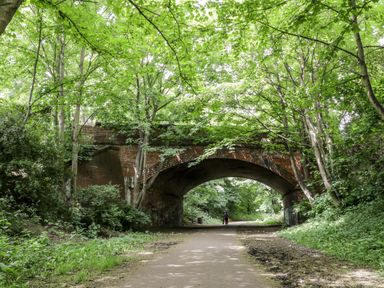 A brick arch bridge over a paved path surrounded by trees and greenery at 89 Caledonia Street in Scarborough