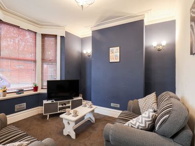 A living room with a gray sofa and a TV on a stand beside a white coffee table at 89 Caledonia Street in Scarborough