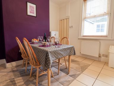 A dining area with a table set for four with wooden chairs near a window at 89 Caledonia Street Scarborough