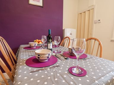 A dining table set with bowls wine glasses and cutlery against a purple wall at 89 Caledonia Street in Scarborough