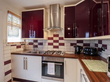 A kitchen with wooden countertops and maroon and white cabinets with a stove and sink at 89 Caledonia Street in Scarborough