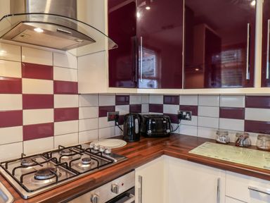 A kitchen corner with gas stove kettle toaster and maroon and white tiles at 89 Caledonia Street Scarborough