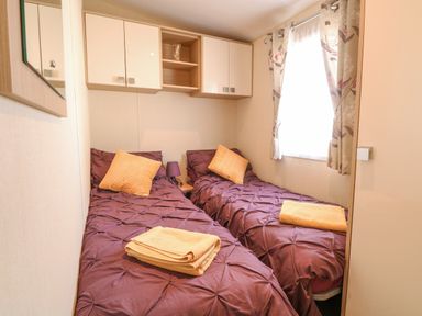 A bedroom with two single beds and yellow towels at Audrey's Lodge Foxburrow Hang in Fritton