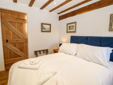 A bedroom with wooden door exposed ceiling beams and a bed at Ty Gwennol in Llanddona near Beaumaris