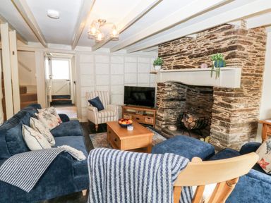 A living room with blue sofas a stone fireplace and a wooden coffee table at Alexanders Cottage in Frogmore