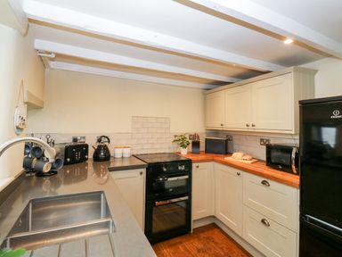 A kitchen with a sink toaster kettle oven microwave and refrigerator at Alexanders Cottage in Frogmore