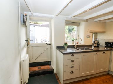 A kitchen with a half door leading outside a window above the sink and cabinets at Alexanders Cottage in Frogmore