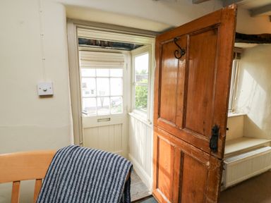 A wooden door partly open next to a windowed door with a chair draped with a striped blanket Alexander's Cottage in Frogmore