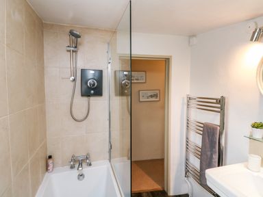 A bathroom with a bathtub shower combo and a towel on a wall radiator at Alexanders Cottage in Frogmore