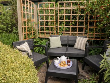 An outdoor seating area with black chairs and a table with tea and scones at Alexanders Cottage in Frogmore