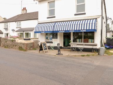 A cafe with a blue and white striped awning and outdoor seating at Alexanders Cottage in Frogmore