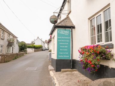 A street view showing a building with a hanging sign for The Globe Inn and flowers on a windowsill at Alexanders Cottage in Frogmore