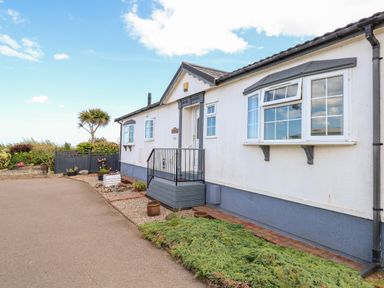 The exterior of a single-story white house with blue trim and a small garden at Seaward in Trimingham