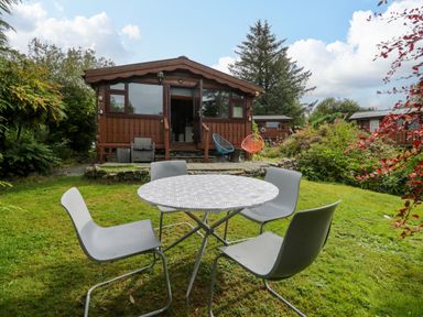 A cabin with seating area and table in the garden at Babbling Brook near Blaenau Ffestiniog