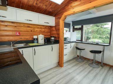 A kitchen with cabinets, sink, and bar stools at Babbling Brook near Blaenau Ffestiniog