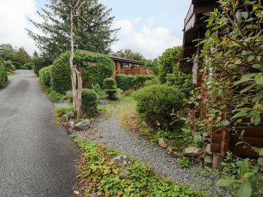 An outdoor area with gravel path and bushes at Babbling Brook in Bron Aber near Blaenau Ffestiniog