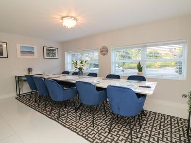 A meeting room with blue chairs around a long white table on a patterned rug at 4 Woodland Park in Northam