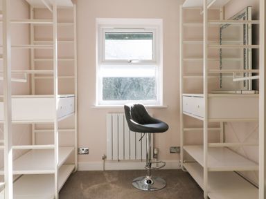 A room with white shelving units a window a gray adjustable chair and a radiator at 4 Woodland Park in Northam