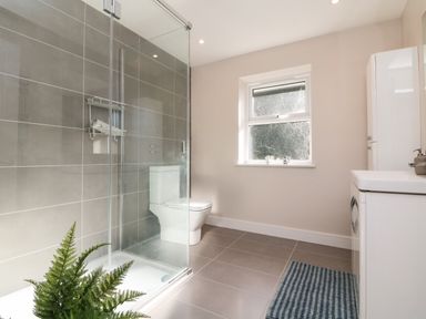A bathroom with a glass shower enclosure toilet window and white sink at 4 Woodland Park in Northam