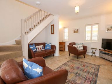 A living room with brown leather sofas and a patterned rug at Angorfa Bach in Abersoch