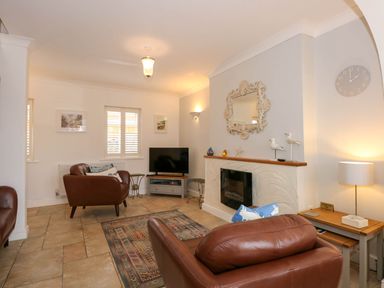 A living room with brown leather chairs a wall mirror and a television at Angorfa Bach in Abersoch