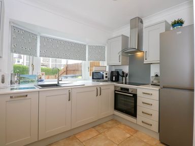 A kitchen with grey cabinets a sink oven and a refrigerator at Angorfa Bach in Abersoch