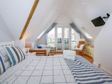 A bedroom with a bed a lamp a sofa a chair and glass doors at Angorfa Bach in Abersoch