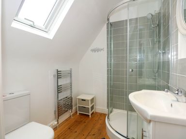 A bathroom with a toilet sink curved glass shower and small cabinet at Angorfa Bach in Abersoch