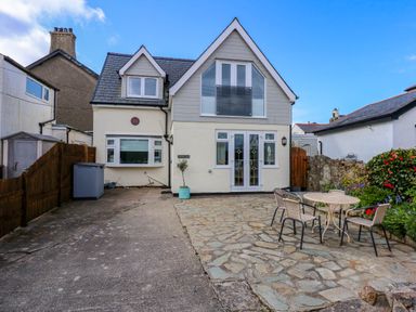 A house with a driveway and patio with table and chairs at Angorfa Bach in Abersoch