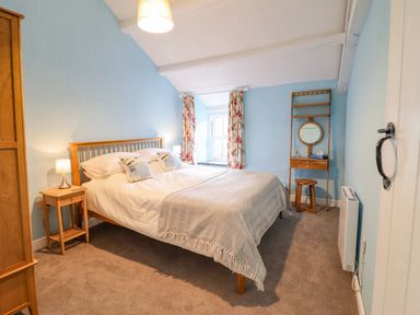 A bedroom with a bed side table wardrobe and dressing table at Preswylfa in Ffestiniog