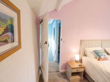 A bedroom with a bed a nightstand and a lamp next to an open door and a framed picture on the wall at Preswylfa Ffestiniog