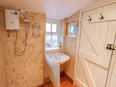 A bathroom with a shower area sink window and a white wooden door at Preswylfa in Ffestiniog