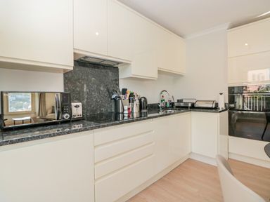 A kitchen with white cabinets black countertop microwave toaster kettle and utensils at Upper Tremorvah in Dartmouth