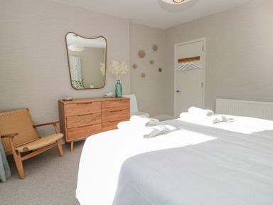 A bedroom with a double bed a wooden dresser a mirror and a chair at Upper Tremorvah in Dartmouth