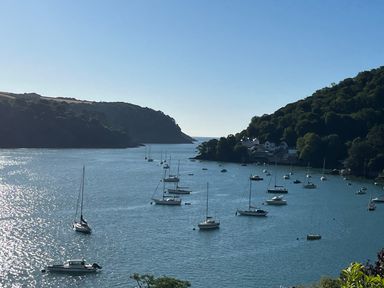 A coastal scene with sailboats anchored in water surrounded by hills at Upper Tremorvah in Dartmouth